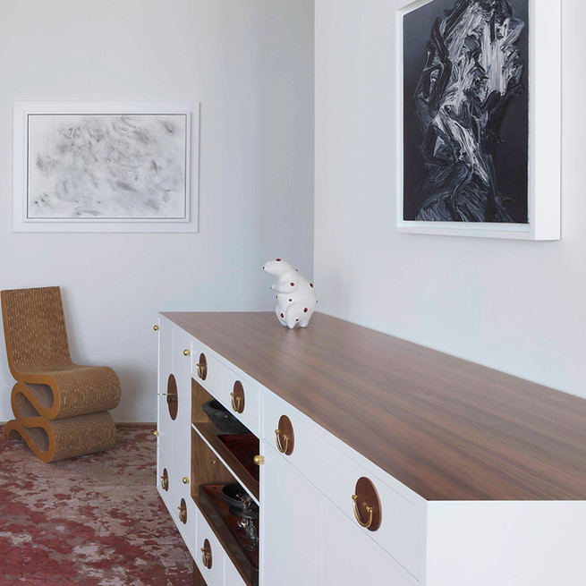 Minimalist interior with framed artwork, a sculptural chair and a wooden console